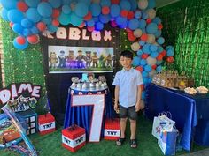 a young boy standing in front of a table with balloons