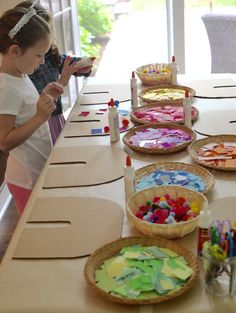 a group of children sitting at a table with paper plates and crayons on it