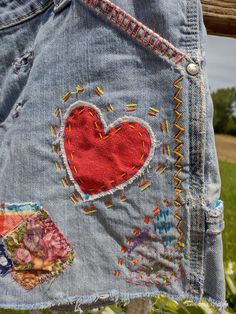 an old pair of jeans with embroidered patches and hearts on them, hanging from a clothes line