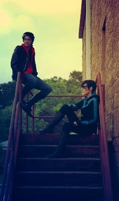 two young men sitting on the steps of a building