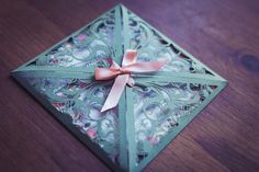 an origami piece with a bow on it sitting on top of a wooden table