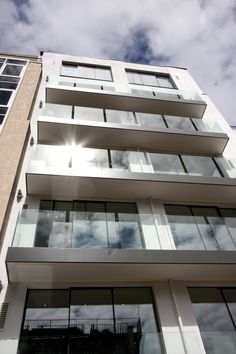 a tall building with lots of windows and balconies on the top floor, against a cloudy blue sky