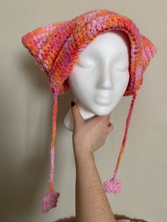 a white mannequin head wearing a pink and orange crocheted hat