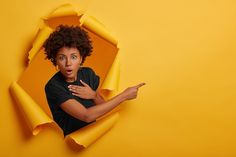 a woman holding a yellow object in her right hand and pointing to it with both hands