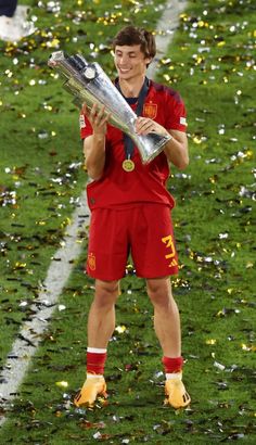 a man holding a trophy on top of a soccer field