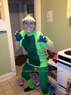 a woman in a green costume with monster hands on her head and arms out, smiling at the camera