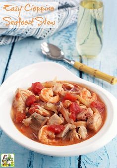 a white bowl filled with pasta and meat in tomato sauce next to a glass of water