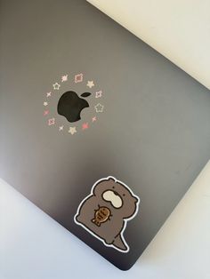 an apple laptop with a bear sticker on the cover and some stars around it