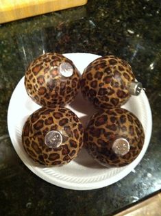 four leopard print glass knobs on a white plate with black granite counter top in the background