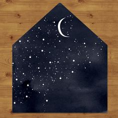 a black envelope with white stars and a half moon on it, against a wood background