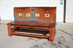 a wooden bench with the word ford painted on it sitting in front of a garage