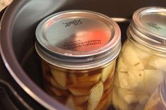 two jars filled with pickles sitting on top of a stove