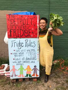 a woman standing next to a sign with vegetables on it