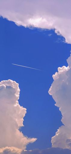 an airplane is flying in the sky with some clouds behind it and a jet trail