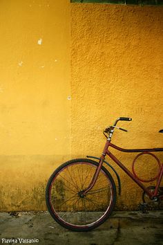 a red bike parked against a yellow wall