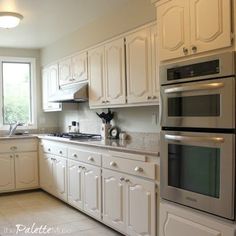 a large kitchen with white cabinets and stainless steel appliances, along with an open window