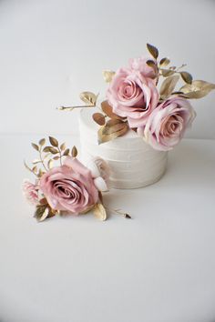 two small white cakes with pink roses on top and gold leafy stems in the middle