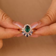 two hands holding an emerald and diamond ring