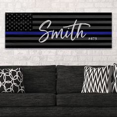 an american flag with the name smith on it in blue and black stripes, is hanging above a couch