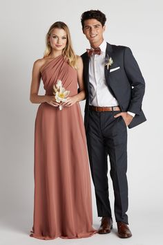 a man and woman standing next to each other in formal wear, posing for the camera