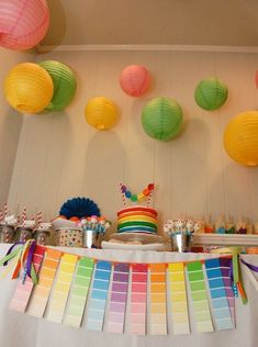 there is a cake and cupcakes on the table with paper lanterns above it