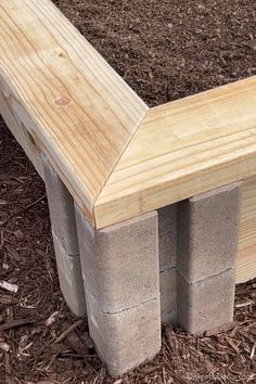 a bench made out of concrete blocks sitting in the ground next to mulchy grass