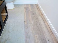 a white toilet sitting in a bathroom next to a wooden floor