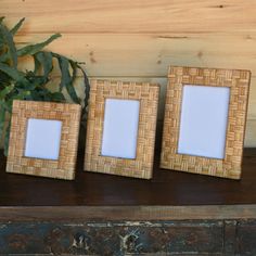 two wooden frames sitting on top of a table next to a vase with flowers in it