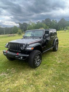 a black jeep parked on top of a lush green field