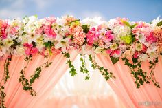 the flowers are hanging over the drapes for an outdoor wedding ceremony in pink and white