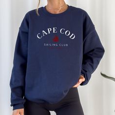 Elevate your seaside style with our Navy Crewneck Cape Cod Sailing Club Sweatshirt. Designed in a deep navy hue reminiscent of the Atlantic, it's the perfect companion for breezy days by the harbor or cozy evenings around a beach bonfire. Whether you're strolling along the picturesque Cape Cod coastline or enjoying a leisurely sail, this sweatshirt, adorned with the club emblem, embodies the maritime charm of the region. Crafted for both comfort and durability, it's equally suited for a day of adventure on the water or simply lounging at your favorite coastal cafe. Join the ranks of coastal enthusiasts and embrace the allure of Cape Cod with our signature sweatshirt. Navy Long Sleeve Marine Top, Marine Style Cotton Crew Neck Top, Navy Sailor Crew Neck Top, Navy Crew Neck Top With Letter Print, Navy Relaxed Fit Crew Sweater, Nautical Cotton Crew Neck Top, Cotton Nautical Crew Neck Tops, Navy Casual Crew Sweatshirt, Navy Casual Crew Neck Sweater