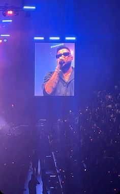 a man standing on top of a stage in front of a screen with a video