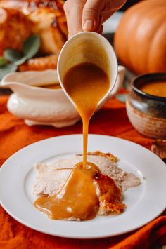 someone pouring gravy on top of some food