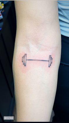 a woman's leg with a barbell tattoo on the lower half of her thigh