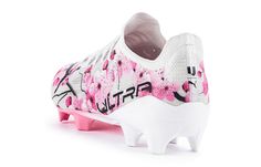 a soccer shoe with pink and white paint splattered on the upper part of it