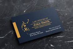 a black and gold business card sitting on top of a marble surface with the name law office of john smith and associates