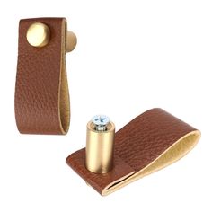 a pair of brown leather cufflinks with a gold plated metal object on top