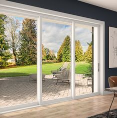 an open living room with sliding glass doors leading to a large lawn and trees in the background