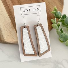 the earrings are made out of wood and have geometric designs on them, along with a plant