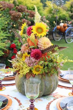 a vase filled with flowers sitting on top of a table next to plates and glasses