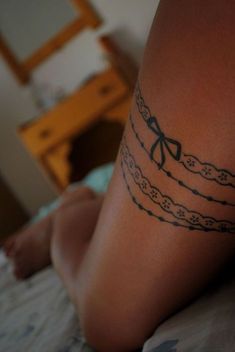 a woman's leg with a tattoo on it that has bows and chains attached to it