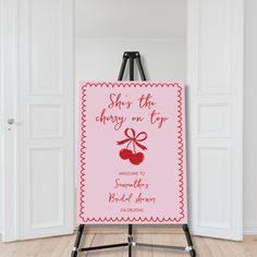 an easel with a cherry on it in front of a white wall and door