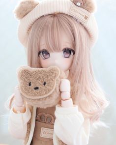 a doll is holding a teddy bear in her hand