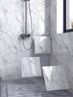 a bathroom with white marble walls and flooring, shower head, and hand held shower faucet