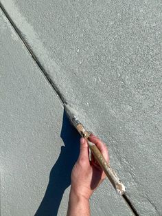 a person is holding an object in their hand on the concrete floor with cement behind them