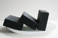 three pieces of black soap on a white plate