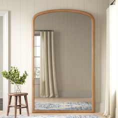 a large mirror sitting on top of a wooden floor next to a chair and table