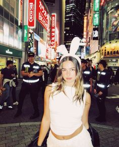 a woman in bunny ears is walking down the street at night with police behind her