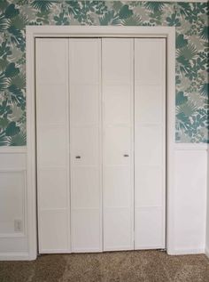 an empty room with white closets and green wallpaper