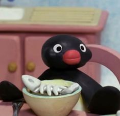 a toy penguin eating food from a bowl